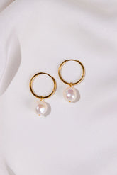 Gold hoop earrings with pearl drops on a white background