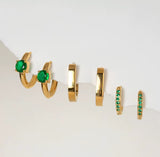 Set of gold hoop earrings with green gemstones on a white background