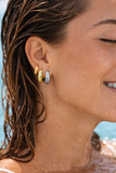 Close-up of a woman wearing gold and silver earrings with a blurred background