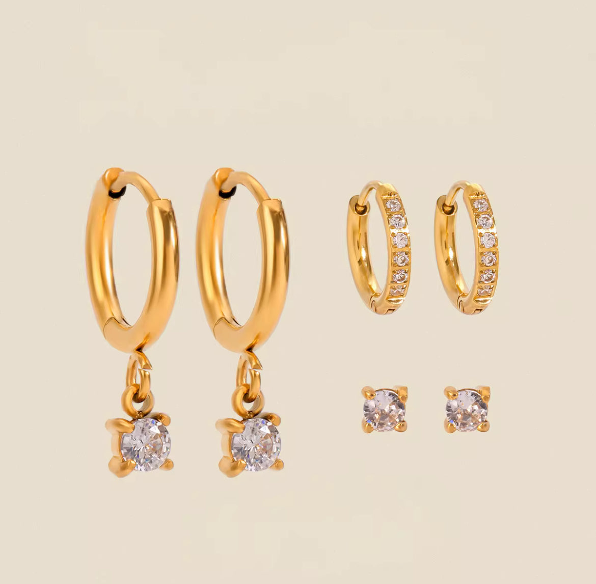 Gold hoop earrings with small round gemstones on a beige background