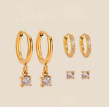 Gold hoop earrings with small round gemstones on a beige background