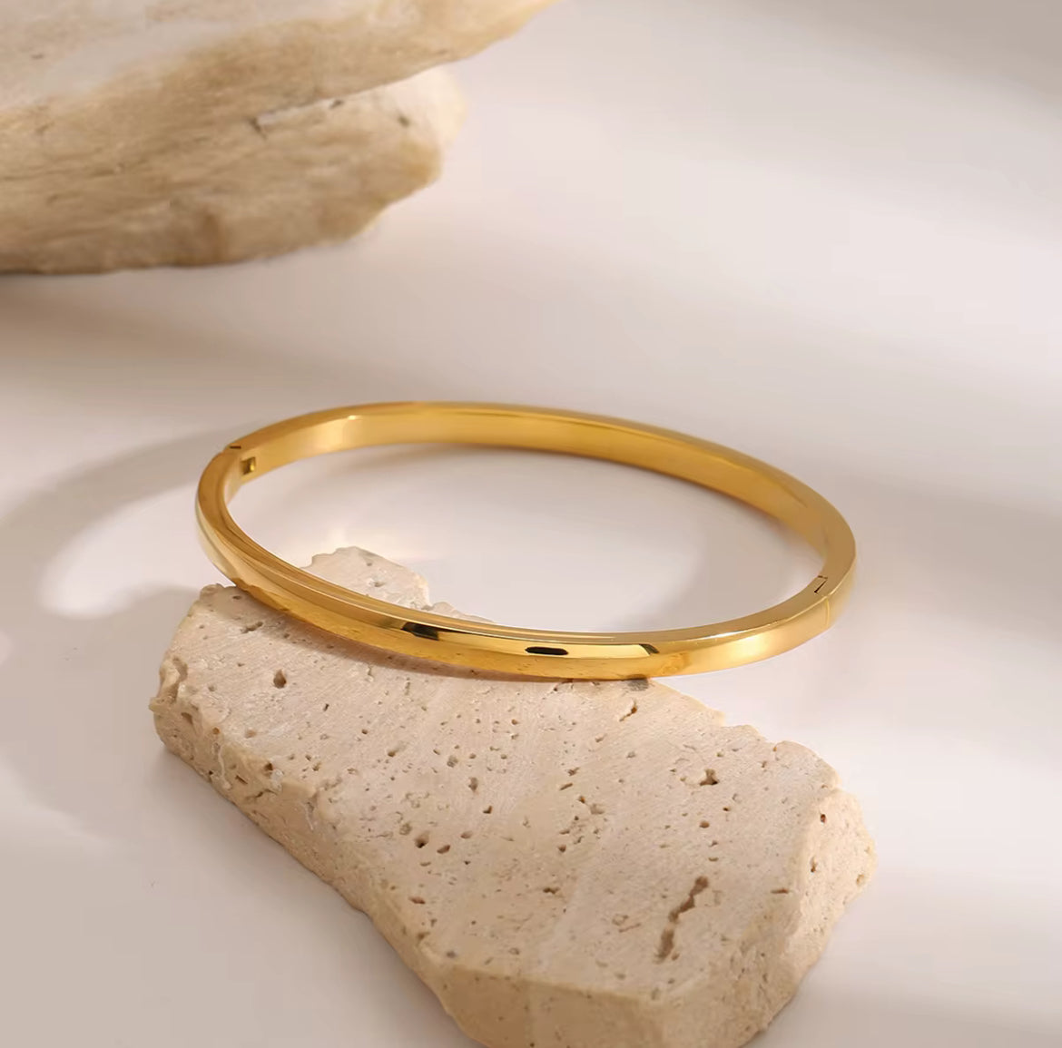 Gold bracelet on a natural stone surface
