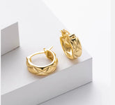 Gold hoop earrings on a white geometric background