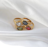 Gold ring with multicolored gemstones on a white fabric background