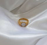 Gold ring with a diamond on a white satin background
