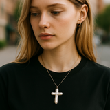 Woman wearing a black shirt and pearl cross necklace with blurred background