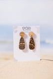 Pair of earrings on a 'Pop Dangle' branded card with a beach background