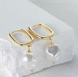 Gold hoop earrings with a '925 Sterling Silver' stamp on a textured white surface.