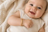 Baby wearing a gold bracelet on a soft beige background