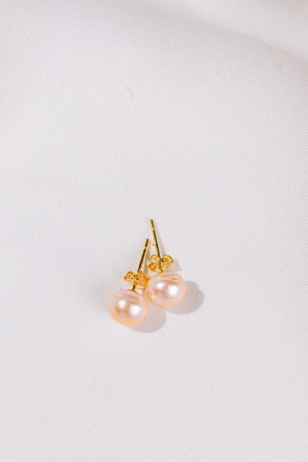 Pair of pearl earrings with gold posts on a light gray background