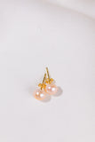 Pair of pearl earrings with gold posts on a light gray background
