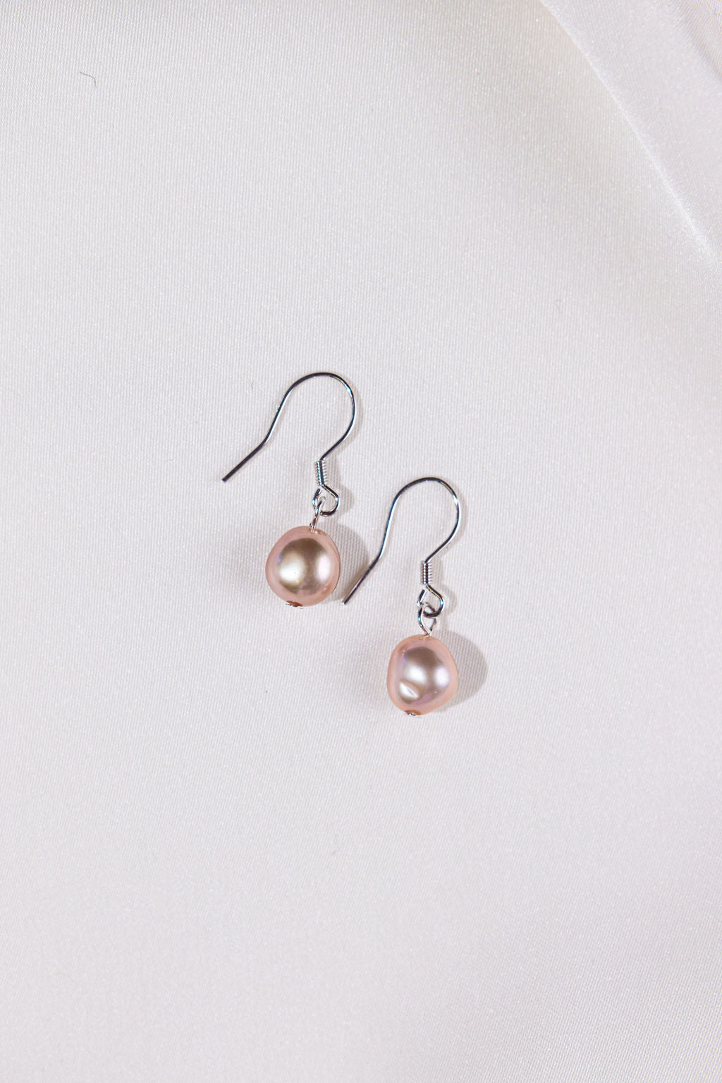 Pair of pink pearl earrings on a white background