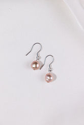 Pair of pink pearl earrings on a white background