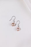 Pair of pink pearl earrings on a white background