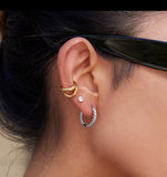 Close-up of an ear wearing gold and silver hoop earrings.