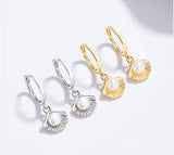 Pair of gold and silver earrings with pearl charms on a white background