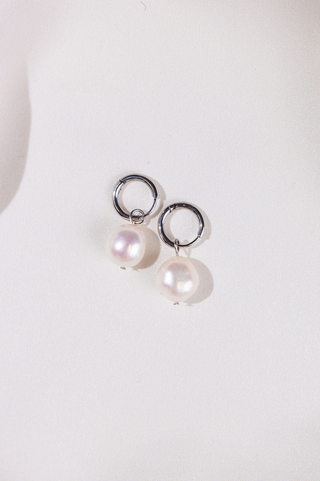 Pearl earrings with silver rings on a white background