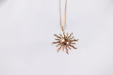 Gold sun-shaped pendant necklace on a white background