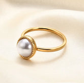 Gold ring with a pearl on a light fabric background