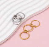 Gold and silver keychains on a pink and white striped fabric background