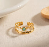 Gold ring with a green gemstone on a beige surface