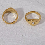 Two gold rings with diamond accents on a textured white surface