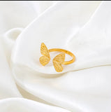 Gold butterfly-shaped ring on a white fabric background