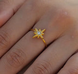 Gold star-shaped ring with a diamond on a person's finger