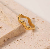 Gold ring with a unique design on a textured beige surface