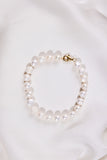 White Pearl bracelet with a gold clasp on a white background