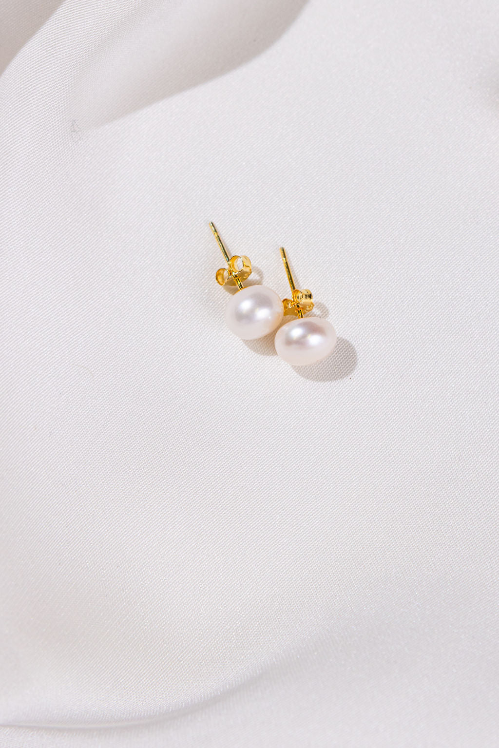 Pearl earrings with gold accents on a white background