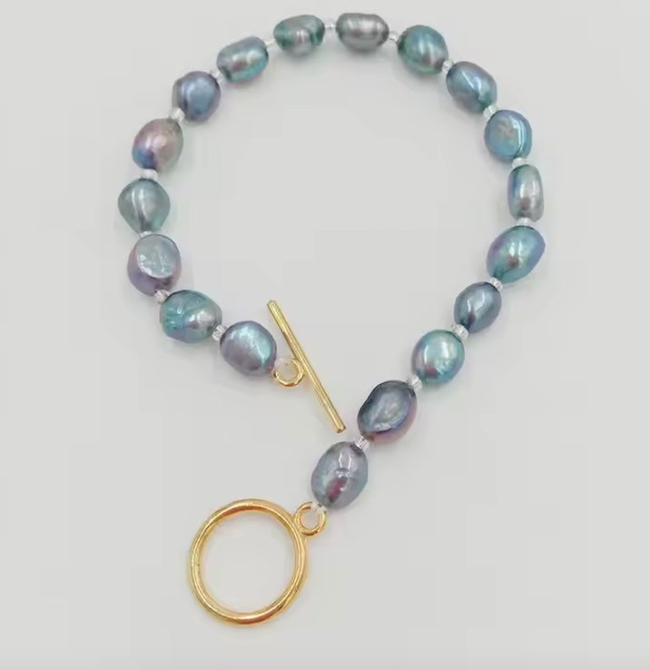 Pearl bracelet with gold clasp on a light gray background