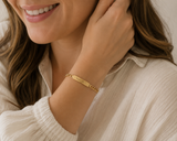 Woman wearing a gold bracelet with a visible brand name, smiling.