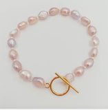 Pearl bracelet with a gold clasp on a light gray background