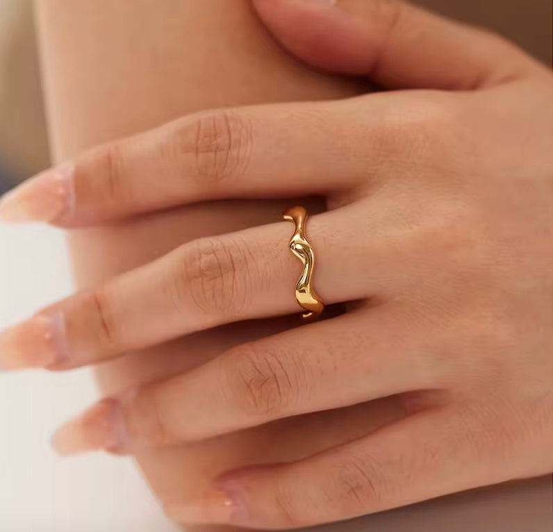 Gold ring on a person's finger with a neutral background