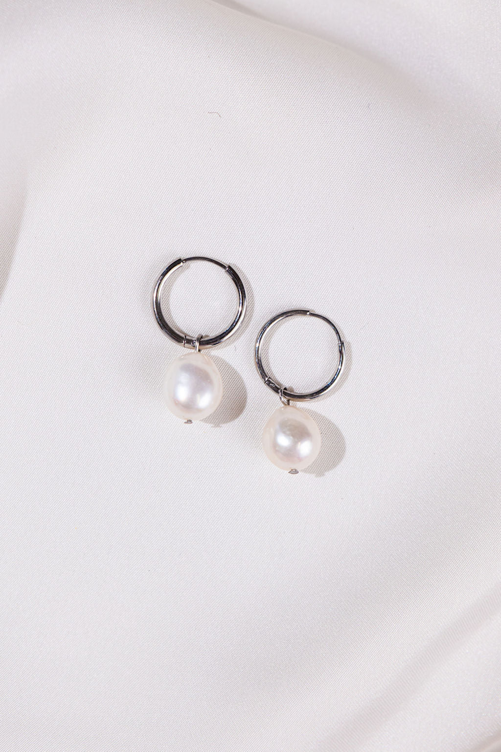 Pearl earrings with silver loops on a white background