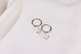 Pair of silver hoop earrings with pearls on a light background