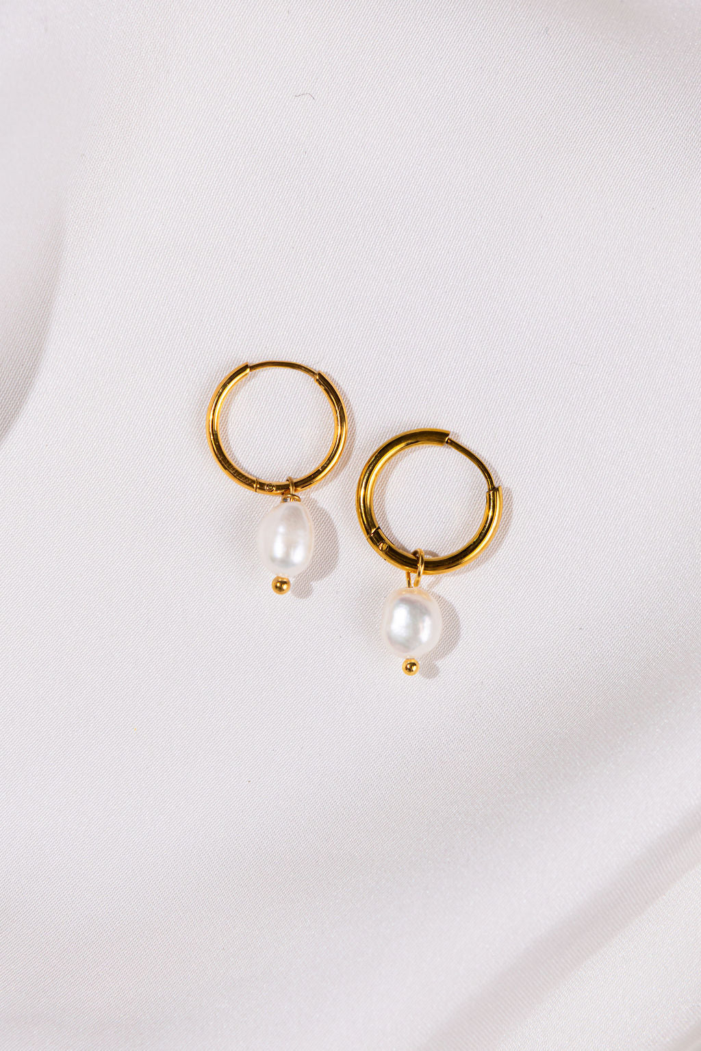 Gold hoop earrings with pearls on a white background