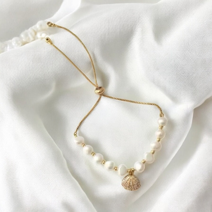Necklace with pearls and a shell pendant on a white fabric background