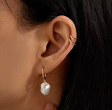 Close-up of an ear wearing a pearl earring with a '925 Sterling Silver' stamp in the corner.