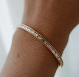 Rose gold bracelet with clear stones on a wrist against a light background