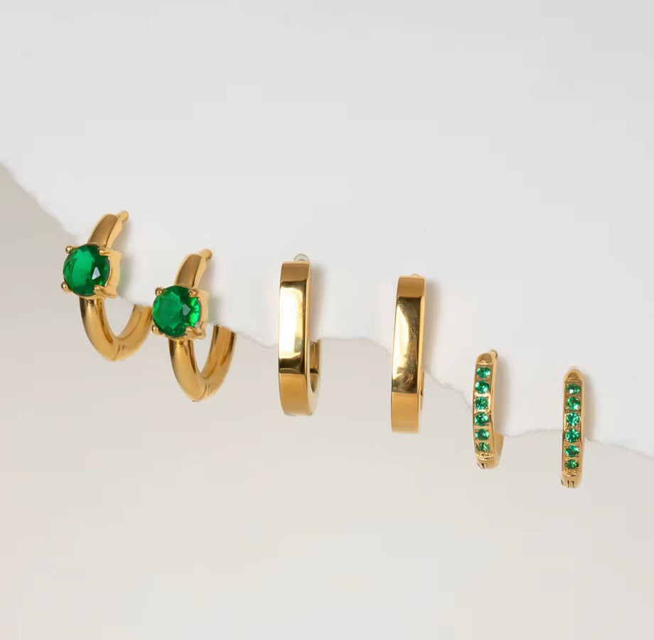 Set of gold hoop earrings with green gemstones on a white background
