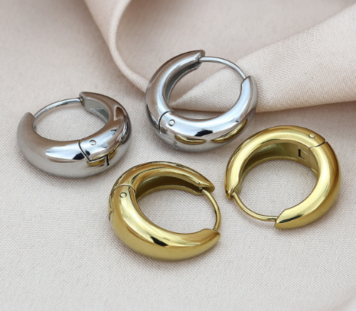Four hoop earrings in silver and gold on a beige fabric background