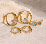 Gold hoop earrings and turquoise stud earrings on a textured beige surface