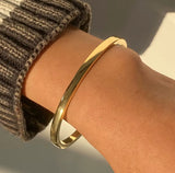 Gold bangle on a wrist with a blurred background