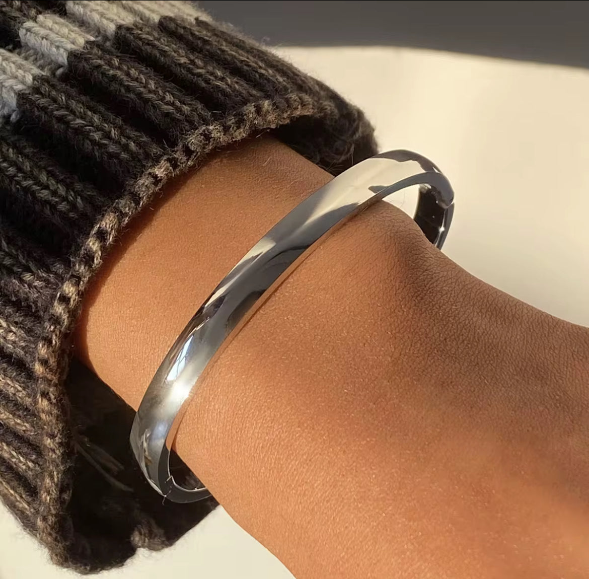 Silver bracelet on a wrist with a textured sleeve
