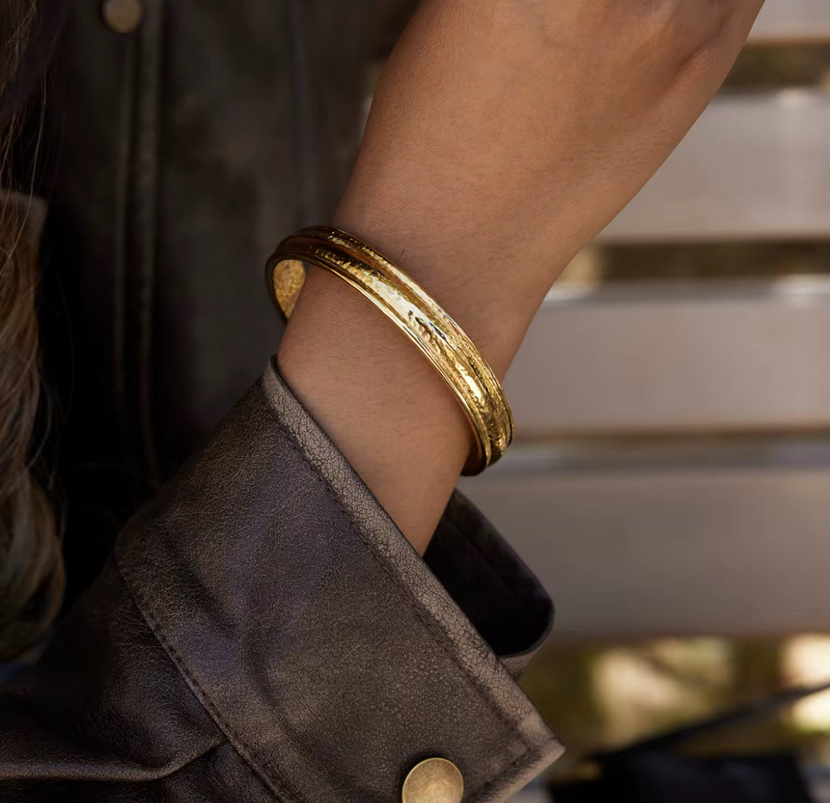 Gold bracelet on a wrist with a blurred background