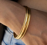 Gold bracelet on a wrist with a blurred background