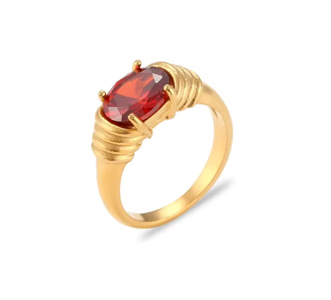 Gold ring with a red gemstone on a white background