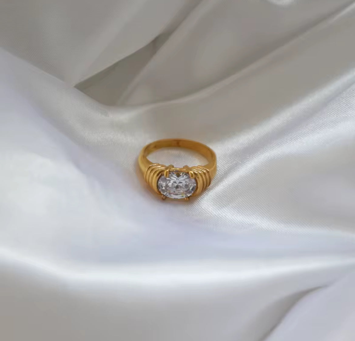 Gold ring with a diamond on a white satin background